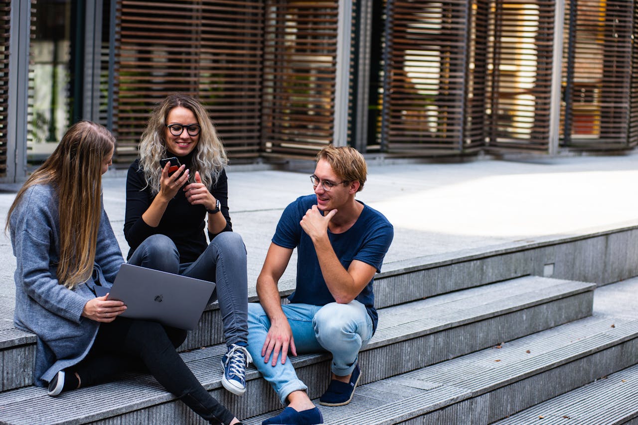 gallery-04 Three young professionals having a friendly chat while sitting on outdoor steps.