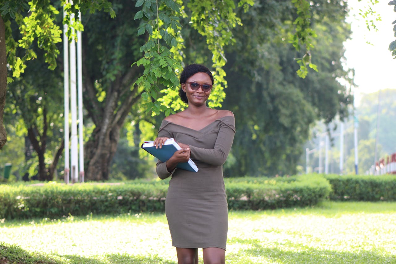 home-img A young woman with books enjoying a sunny day outdoors on a university campus.