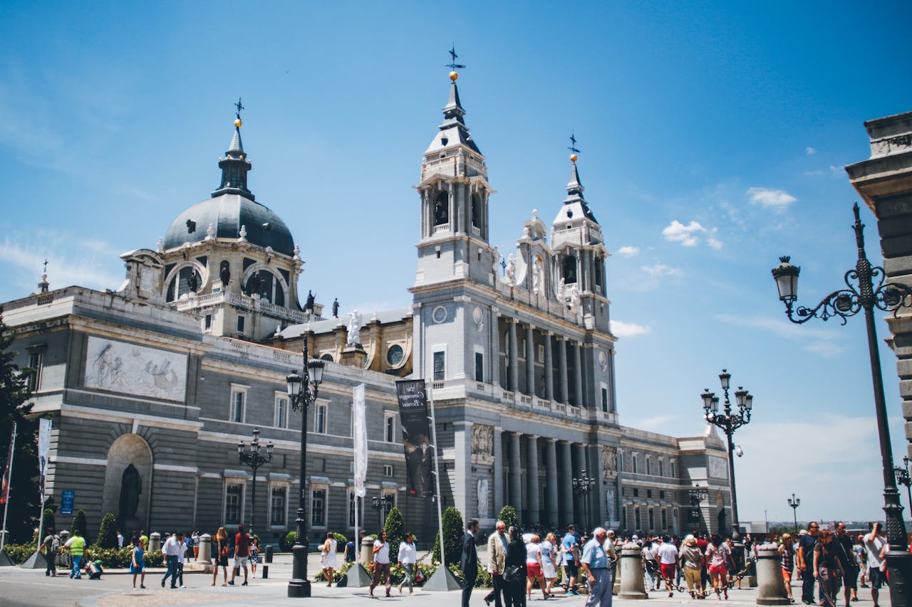 about-img Almudena Cathedral in Madrid with tourists on a bright summer day.
