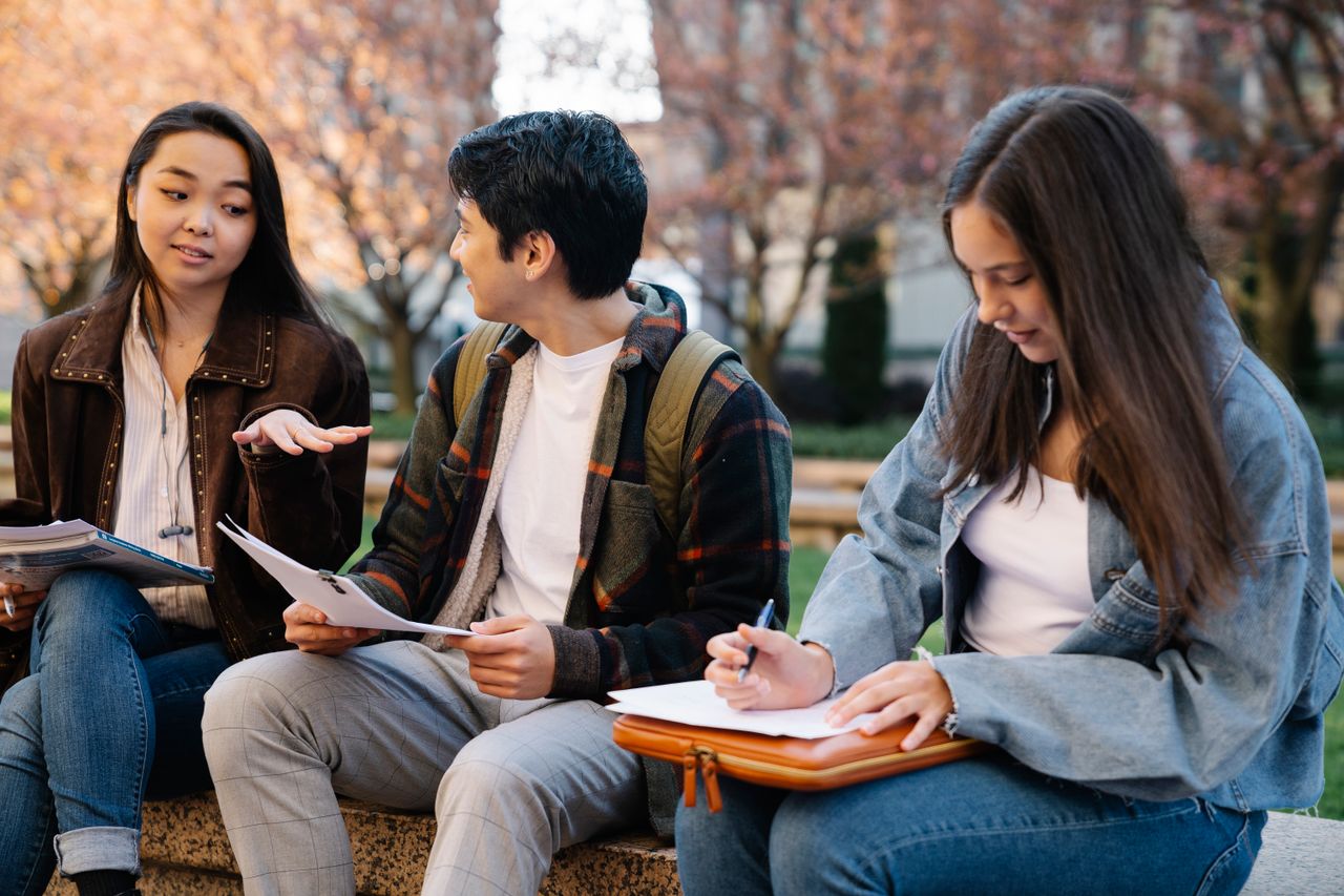project-01-b Three students sitting and studying together in a campus setting.