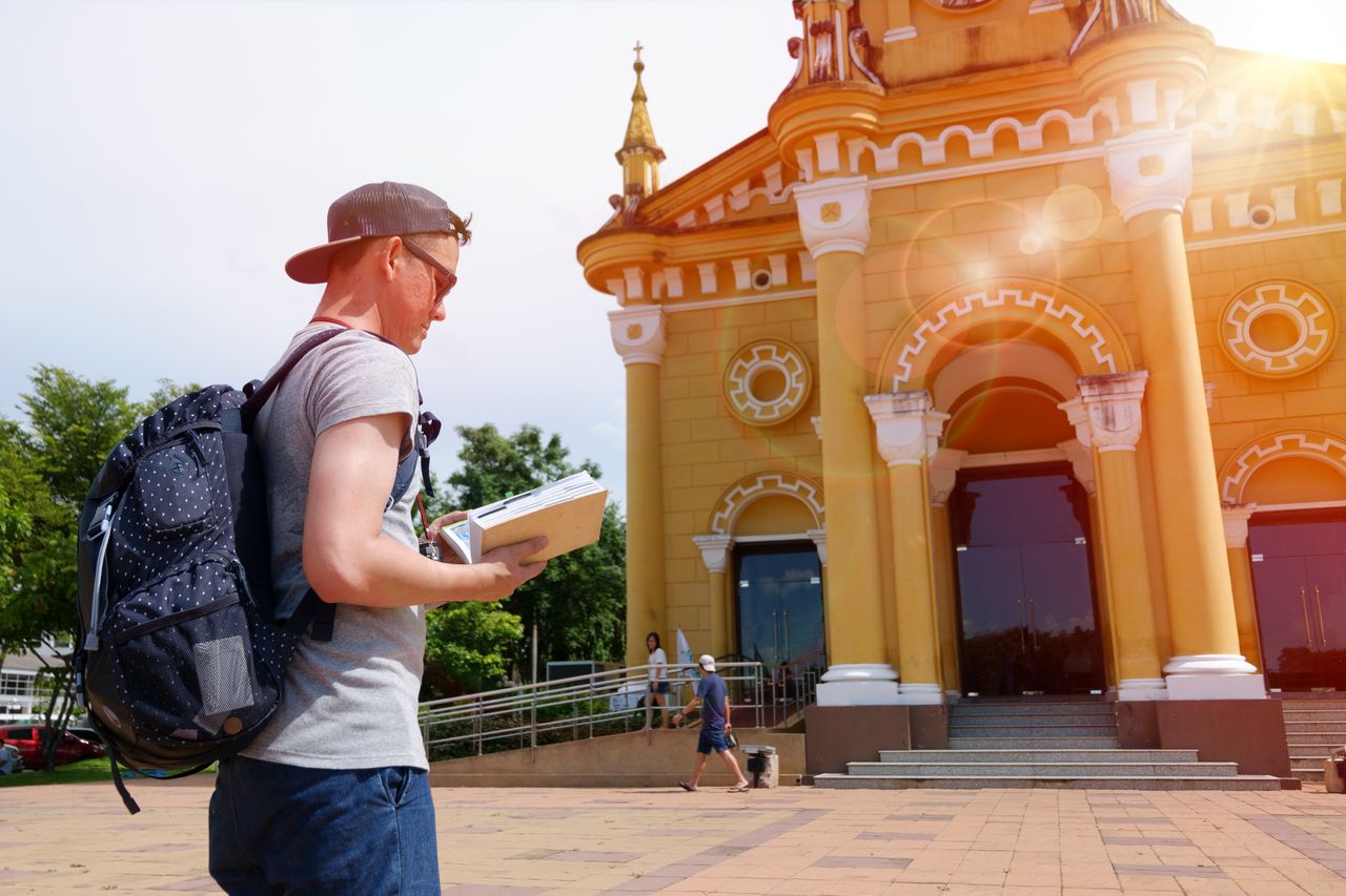 engagement-photography-03 A young traveler examines a guidebook near a historic urban building on a sunny day.